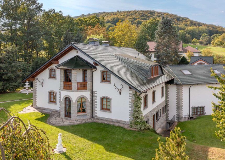 Forsthaus mit tannengrünem Biberdach, zwei verschiedene Schnitte, und zwei verschiedenen Firstziegeln aus der Gartenansicht.