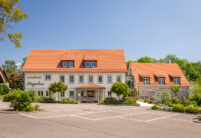 Landhotel mit Biberschwanzziegel Segmentschnitt in naturrot in der Gesamtansicht mit Nebengebäude.