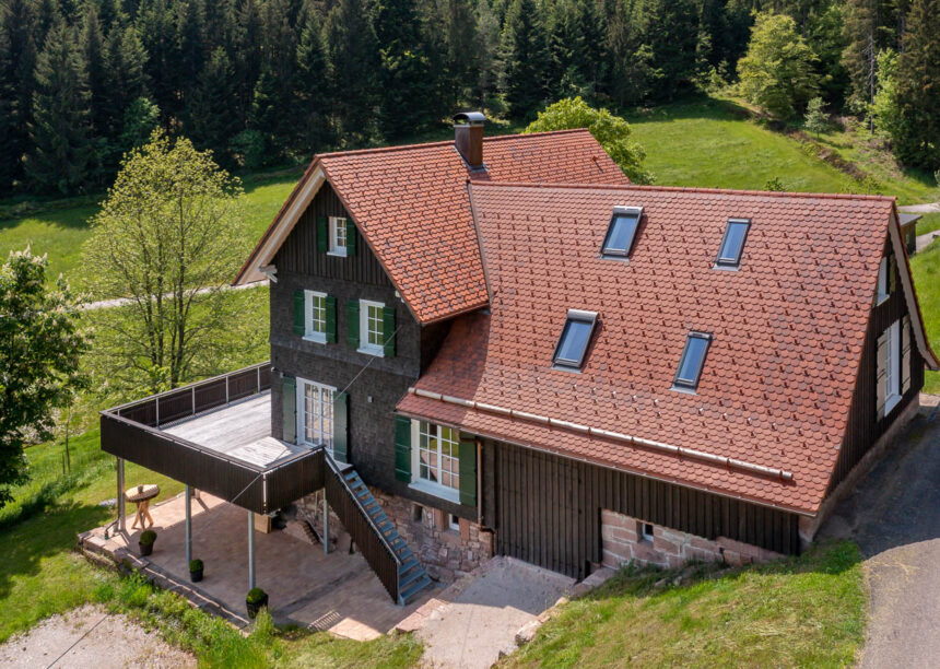 Typisches Schwarzwaldhaus mit geflammten Biber im Fokus die Rundholzhalterung aus der Luft fotografiert.