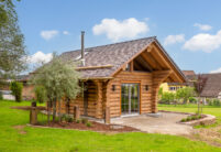 Holzhaus mit Biberschwanzziegeln in effektgrau toll eingebettet im schön angelegten Garten.