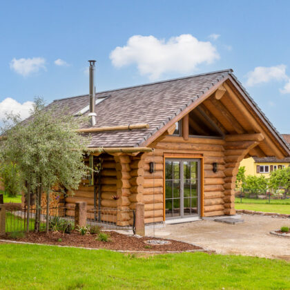 Holzhaus mit Biberschwanzziegeln in effektgrau toll eingebettet im schön angelegten Garten.