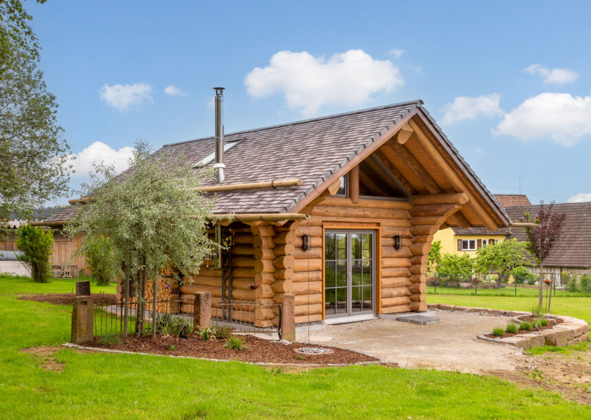 Holzhaus mit Biberschwanzziegeln in effektgrau toll eingebettet im schön angelegten Garten.
