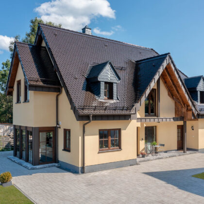 Biber Rundschnitt in edelmarone auf Walmdach/Satteldach eines Einfamilenhauses in der Gesamtansicht.