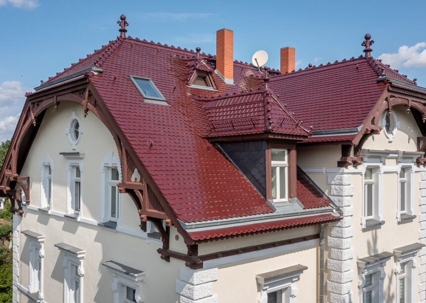 Denkmalgeschützte Villa mit bordeauxroten Biberschwanzziegeln mit der Giebelseite und Dachfläche im Bild.