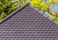 Traditionelles Einfamilienhaus mit Krüppelwalmdach, gedeckt mit Biberschwanzziegel in edelschwarz