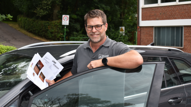 Außendienstkollege steht an seinem Dienstfahrzeug