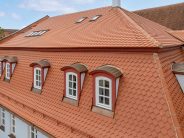 Mehrfamilienhaus mit Bibern in Rautespitz im traditionellen naturrot gedeckt mit Fokus auf die kunstvollen Gauben