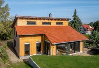 Garteneinblick von Einfamilienhaus mit Dachziegel J160 in altrot mit schöner Holzfassade