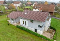 Rückansicht von Wohnhaus Dachziegel Z10 von Jacobi auf Baustilhaus in der Oberfläche edelweinrot mit schmuckvollem Firstanfänger der Serie F6v und Nebengebäude mit dem gleichen Ziegelmodell