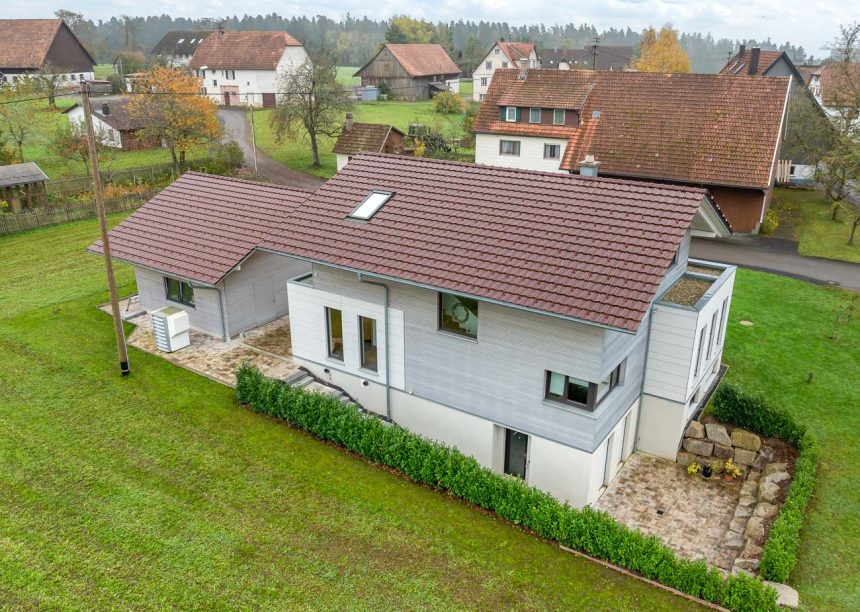 Rückansicht von Wohnhaus Dachziegel Z10 von Jacobi auf Baustilhaus in der Oberfläche edelweinrot mit schmuckvollem Firstanfänger der Serie F6v und Nebengebäude mit dem gleichen Ziegelmodell