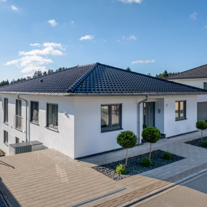Unser beliebtester Dachziegel J11v hin im stylischen spacegrau auf Bungalow mit Walmdach von der Straßenansicht aus fotografiert mit modernem Vorgarten