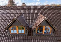 Jacobi Referenzobjekt mit Dachziegel J11v in edelbraun auf verklinkertem, saniertem Einfamilienhaus, mit Details von den beiden Satteldachgauben und Firstanfänger aus der Serie F6v