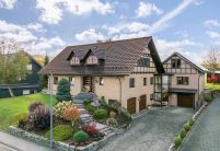 Jacobi Referenzobjekt mit Dachziegel J11v in edelbraun auf verklinkertem, saniertem Einfamilienhaus mitten im Grünen mit Vorgarten und Hofeinblick