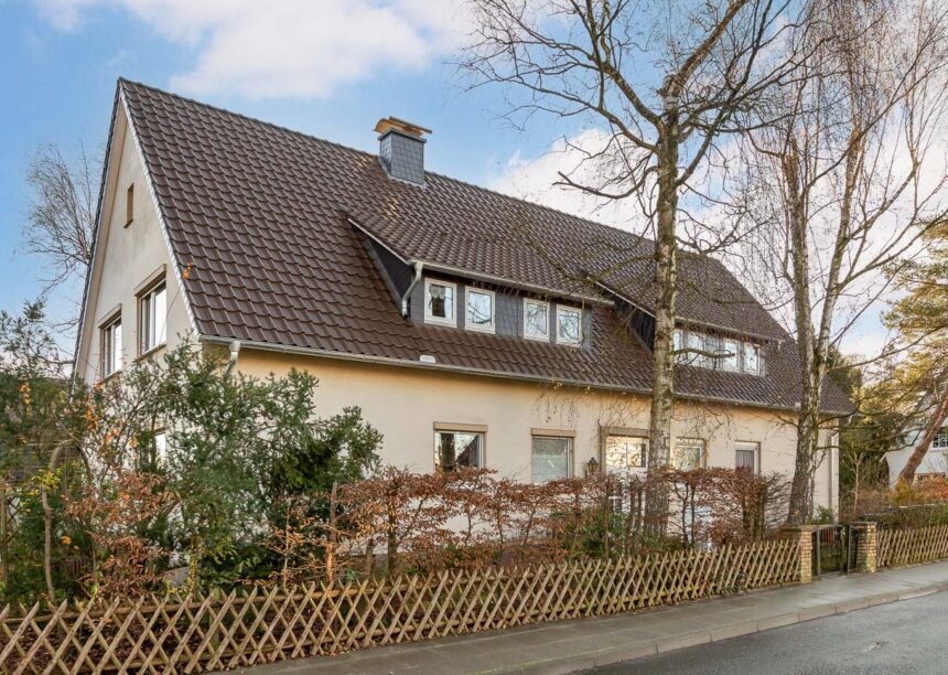 Einfamilienhaus mit Flachdachziegel J11v in dunkelbraun in der Gesamtansicht mit Gartenzaun.