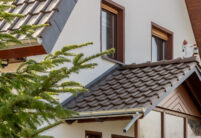 Dachsanierung eines Einfamilienhauses mit dunkelbraunem J11v. Auf dem Foto gut sichtbar Vordach mit Firstfigur.