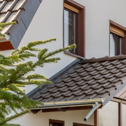 Dachsanierung eines Einfamilienhauses mit dunkelbraunem J11v. Auf dem Foto gut sichtbar Vordach mit Firstfigur.