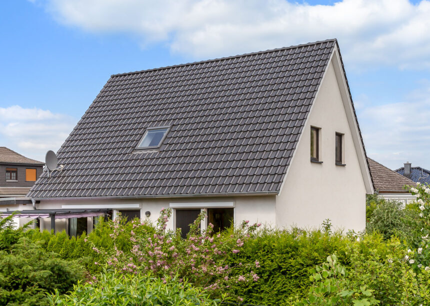 Klassisches Einfamilienhaus mit zeitlosem Flachdachziegel J11v in altschwarz mit toller Hecke.