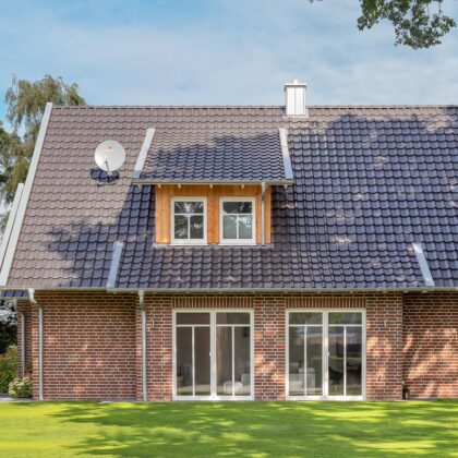 Kleines Klinkerhaus mit Flachdachziegel J11v in altschwarz aus der Gartenperspektive.