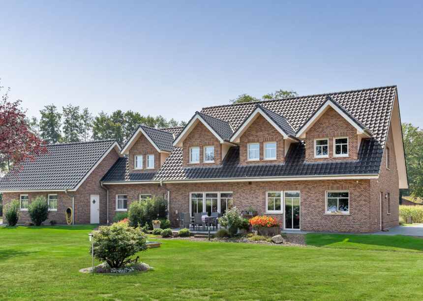 Klinkerhaus mit altschwarzem Flachdachziegel J11v frontal aus dem Garten fotografiert.