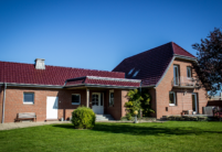 Einfamilienhaus in der Natur mit Flachdachziegel J11v in der Edelengobe edelweinrot.