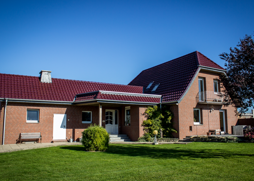 Einfamilienhaus in der Natur mit Flachdachziegel J11v in der Edelengobe edelweinrot.