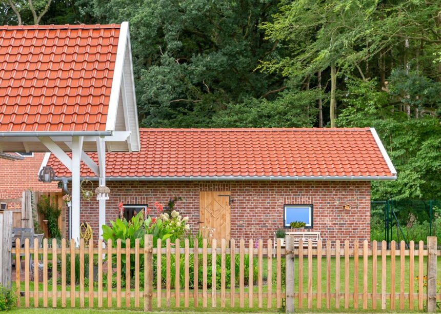 Modernes Bauernhaus mit edlem J11v in edelkupfer und Holzlattenzaun.
