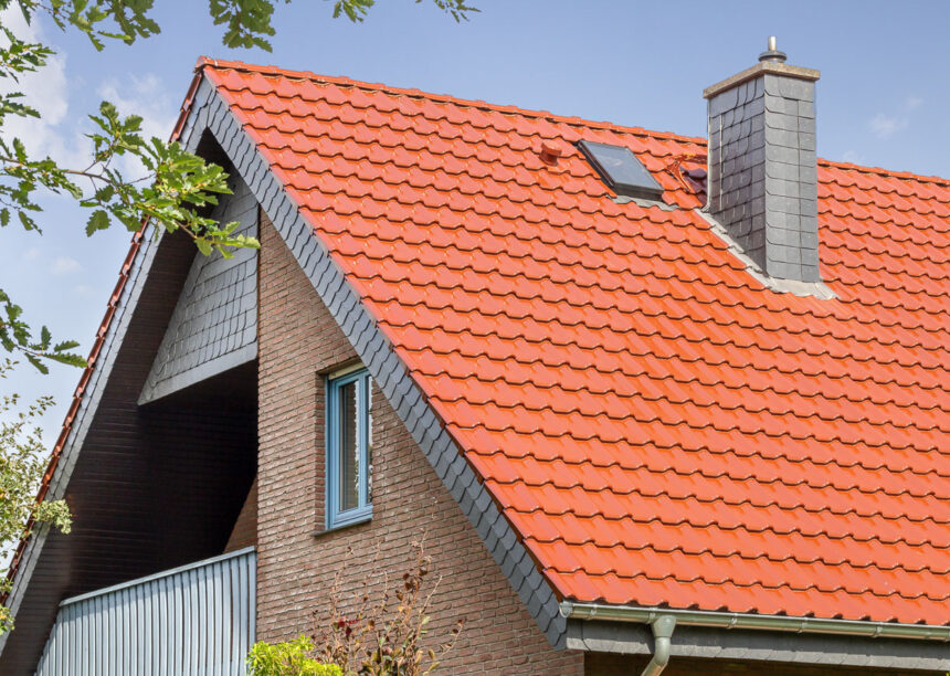 Giebelseite eines Klinkerhauses mit überdachtem Balkon. Auf dem Steildach unsere Flachdachpfanne J11v in edelkupfer.