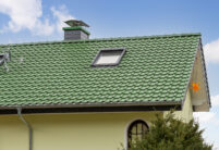 Sanierter Bau aus den 70/80er Jahren mit auffallend grünem Dach mit Fokus auf die Firstreihe und Dachfläche.