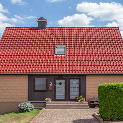 Saniertes Einfamilienhaus mit strahlend rotem Dach, kombiniert mit brauner Klinkerfassade