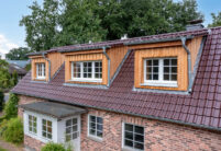 Glasur bordeauxrot matt auf Klinkerhaus mit Fokus auf die holzvertäfelten Gauben.