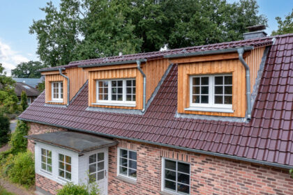 Glasur bordeauxrot matt auf Klinkerhaus mit Fokus auf die holzvertäfelten Gauben.