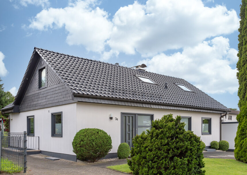 Gesamtansicht von saniertem Einfamilienhaus mit Satteldach und Gaube, gedeckt mit Dachziegel J11v mit Schneefanggitter