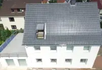 Vogelperspektive von Haus mit zwei Stockwerken und Dachterrasse und J11v Dach in der dezenten Glasur lavagrau matt