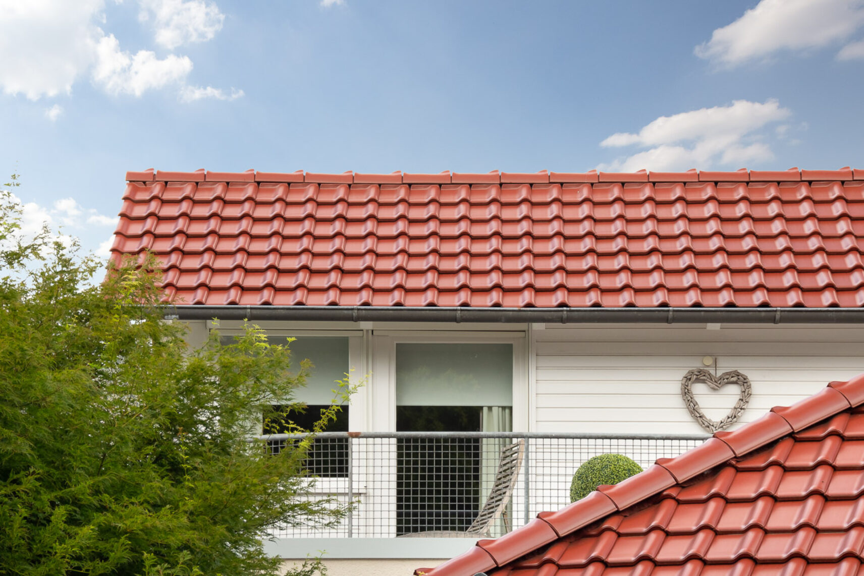 Einfamilienhaus mit Satteldach und Dachziegel J11v in toskanarot matt. Der Bildfokus liegt den First und Deckbild