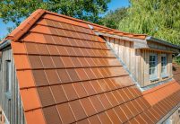 Traumhaftes Einfamilienhaus mit Klinkerfassade, Holzelementen und stilvollem Dach mit Solarziegel Stylist-PV in rotbraun mit Giebel- und Gaubendetails