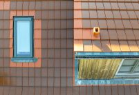 Traumhaftes Einfamilienhaus mit Klinkerfassade, Holzelementen und stilvollem Dach mit Solarziegel Stylist-PV in rotbraun mit Details von der Gaube