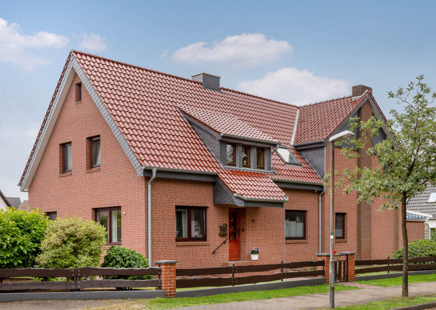 Großer Haus mit Klinkerfassade und Flachdachziegel J13v in edelkupfer auf dem Dach