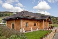 Rustikales Holzhaus mit Flachdachziegel J13v in vulkanschwarz auf dem Dach