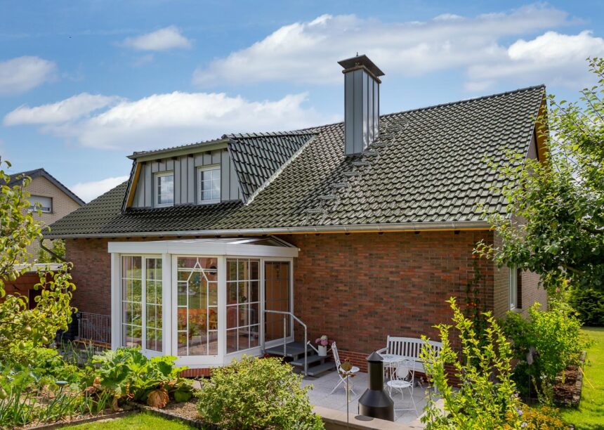 Rückansicht eines Klinkerhauses mit Wintergarten, Flachdachziegel J13v in tannengrün auf dem Dach