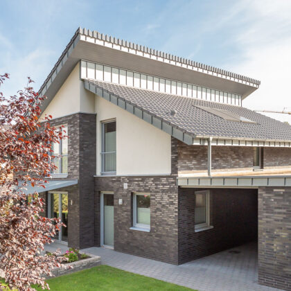 Modernes Einfamilienhaus mit Pultdach, gedeckt mit silbergrauem Flachdachziegel J13v