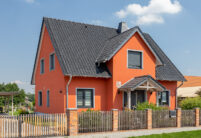 Einfamilienhaus mit orangener Fassade und schwarzem Dach