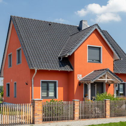 Einfamilienhaus mit orangener Fassade und schwarzem Dach