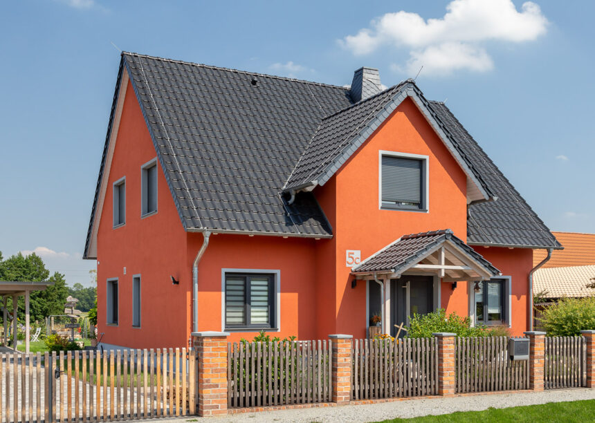 Einfamilienhaus mit orangener Fassade und schwarzem Dach