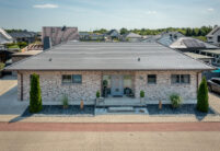 Sueddeutscher Biber Rundschnitt in silbergrau auf Walmdach-Bungalow mit Klinkerfassade.