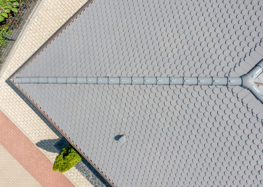 Sueddeutscher Biber Rundschnitt in silbergrau auf Walmdach-Bungalow mit Klinkerfassade mit Fokus auf Biberfirst F3, 3-achsige Walmkappe und Saniluefter.