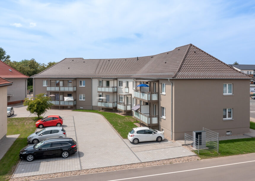 Flachdachziegel J11v in dunkelbraun auf Mehrfamilienhaus hier die Gesamtansicht mit Parkplatz.