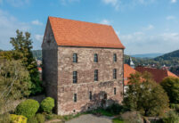 Historisches Muthaus mit Krempziegel K1 in Harzerbunt mit Dorfansicht im Hintergrund