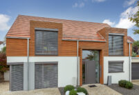 Flachziegel WALTHER Stylist® in rotbraun auf Satteldach mit formschöner Gaube auf modernem Haus mit Holzverkleidung
