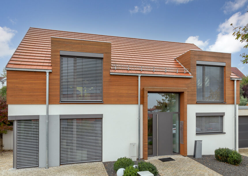 Flachziegel WALTHER Stylist® in rotbraun auf Satteldach mit formschöner Gaube auf modernem Haus mit Holzverkleidung