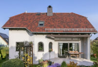 Cottage Flachziegel auf Walmdach eines Einfamilienhauses in der Gesamtansicht mit Terrasse